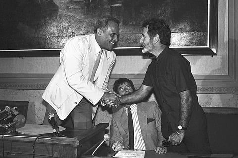 South African writer Breyten Breytenbach, right, and American actor and singer Harry Belafonte shake hands during a press conference in Paris, on June 18, 1986.