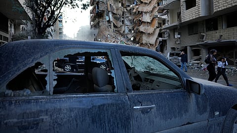 Residents pass in front of a destroyed building that was hit Sunday night in an Israeli airstrike in Dahiyeh, in the southern suburb of Beirut, Lebanon.