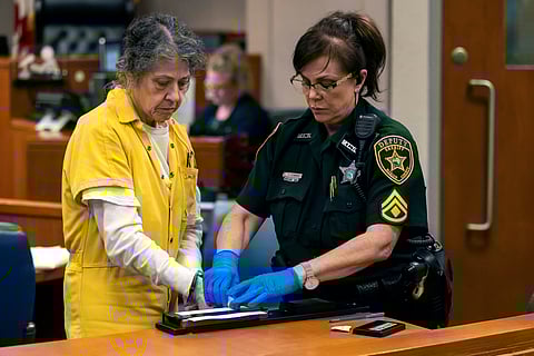 Susan Lorincz, left, who fatally shot a Black neighbor through her front door during an ongoing dispute, is finger printed after she was sentenced to 25 years in prison at a court hearing Monday, Nov. 25, 2024, in Ocala, Fla.
