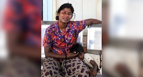 Ishwari, a relative of Kaliyappan, one of the deceased, waits with her son in front of the Thrissur General Hospital mortuary for the mortal remains of the accident victims