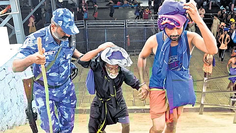 A Rapid Action Force officer assisting an aged devotee climb the steps of Valiyanadapandal to reach the holy steps at Sabarimala.