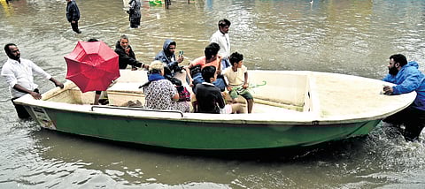 Stranded residents being carried on a boat at Muthamil Nagar, Kodungaiyur, in Chennai on Saturday.