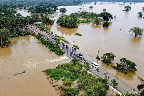 People walk along a street at a neighborhood partially submerged in floodwater as cyclone Fengal is forecasted to make landfall in Puttalam on November 29, 2024.