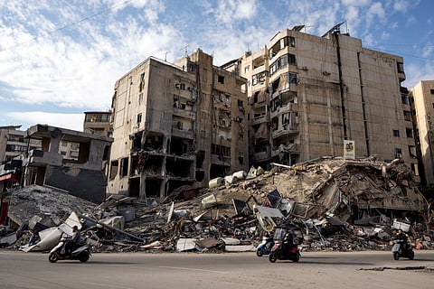 People on their scooter drive past destroyed buildings in Dahiyeh, Beirut, Lebanon, Friday, Nov. 29, 2024.