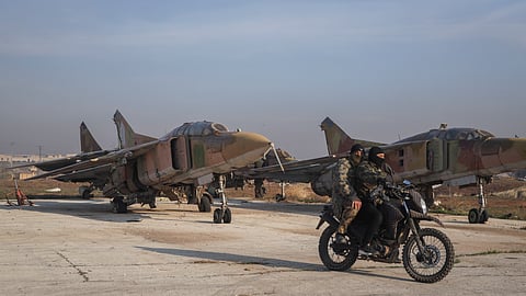 Syrian opposition fighters ride on a motorcycle past Syrian army planes at the Al-Nayrab military airport after they took control of the facility in the outskirts of Aleppo, Syria, Monday, Dec. 2, 2024.