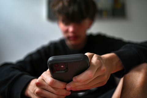 A teenager uses his mobile phone to access social media, Sydney.