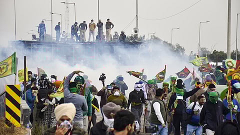 Farmers run for cover after police used teargas to disperse them during their protest at the Shambhu border, in Patiala district, Sunday, Dec. 8, 2024.