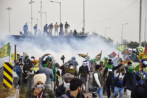 Farmers run for cover after police used teargas to disperse them during their protest at the Shambhu border, in Patiala district, Sunday, Dec. 8, 2024.