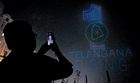 A man takes a picture of drone show held at Secretariat as part of the Praja Palana Vijayotsavalu programme in Hyderabad.