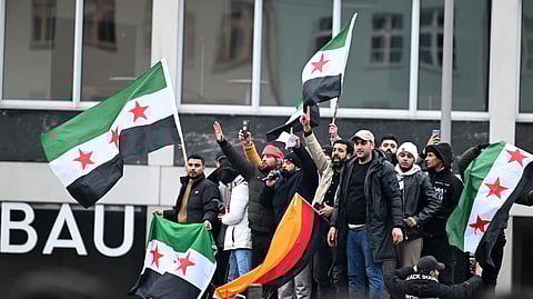 Members of the Syrian community hoist flags of Syria and Germany as they rally on December 8, 2024, in Berlin, Germany, to celebrate the end of Syrian dictator Bashar al-Assad's rule after rebel fighters took control of the Syrian capital Damascus overnight.