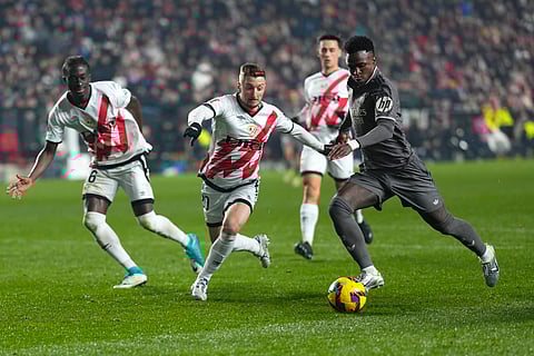 Rayo's Ivan Balliu, centre, challenges for the ball with Real Madrid's Vinicius Junior during the Spanish La Liga soccer match between Rayo Vallecano and Real Madrid at the Vallecas stadium in Madrid, Spain, Saturday, Dec. 14, 2024.