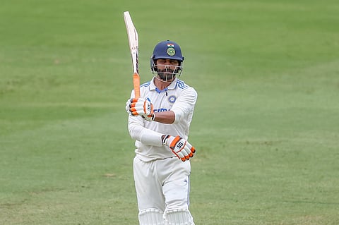 India's Ravindra Jadeja raises his bat as he celebrates after scoring fifty runs during play on day four of the third cricket test between India and Australia at the Gabba.