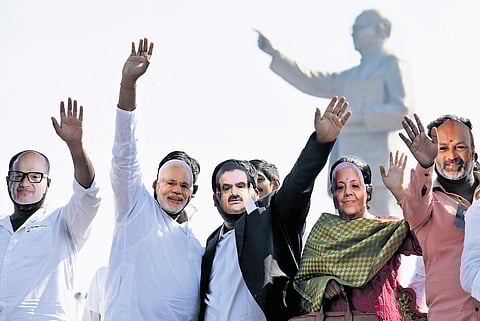 Congress activists wear masks of Prime Minister Narendra Modi and Gautam Adani during the ‘Chalo Raj Bhavan’ protest in Hyderabad on Wednesday.