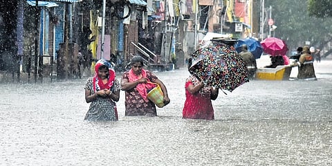 People wade through an flooded road in Chennai