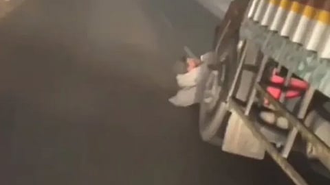 A video grab shows the man stuck under the truck