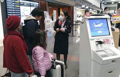 staff member of Japan Airlines helps customers at the Haneda airport in Tokyo, Thursday, Dec. 26, 2024, after the airlines said it was hit by a cyberattack.