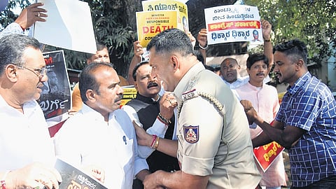 BJP leaders argue with a police officer before being detained during their protest and launch of a poster campain seeking the resignation of RDPR Minister Priyank Kharge, in Bengaluru on Tuesday