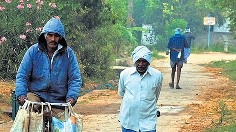 People walk with their heads covered on a chilly morning in Karimnagar on Friday