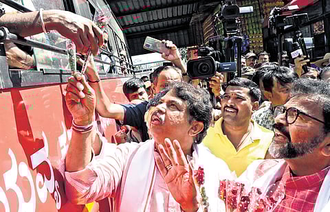 Leader of Opposition in the Assembly R Ashoka and his Council counterpart Chalavadi Narayanaswamy present flowers to commuters in protest against the 15% hike in bus fares, in Bengaluru on Friday