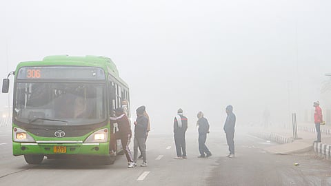 People board a bus during a cold and foggy winter morning near Akshardham temple, in New Delhi.