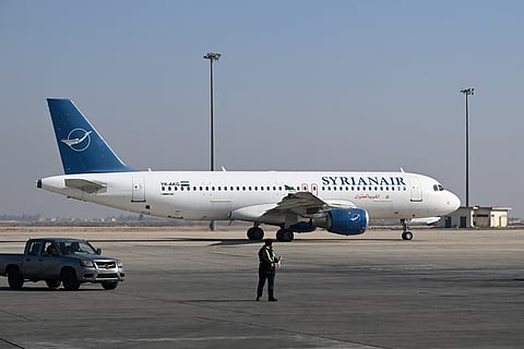 An airport worker walks on the tarmac next to a Syrian Air plane at the Damascus International Airport on January 7, 2025.