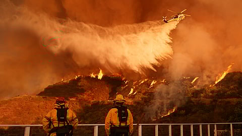 Firefighters watch as water is dropped on the Palisades Fire in Mandeville Canyon Saturday, Jan. 11, 2025, in Los Angeles.