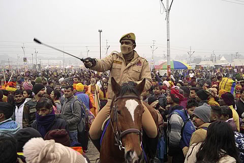 A policeman controls the crowd at Sangam, the confluence of the Rivers Ganges, Yamuna and mythical Saraswati