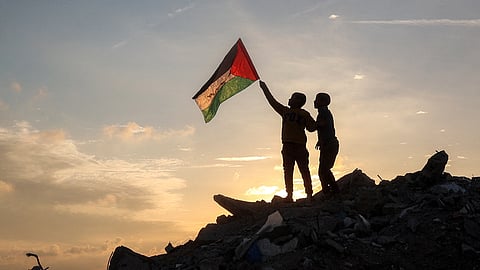 A boy runs with a Palestinian flag atop a mound of rubble at a camp for people displaced by conflict in Bureij in the central Gaza Strip on January 17, 2025, following the announcement of a truce amid the ongoing war between Israel and Hamas.