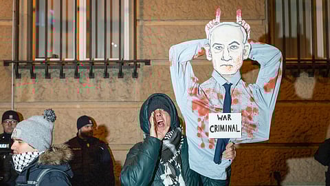 A protester holds up a banner depicting Israel's Prime Minister Benjamin Netanyahu reading "War Criminal" during a demonstration in Warsaw, Poland, on January 10, 2025.