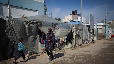 A woman and a child walk outside their tent at a camp for displaced Palestinians in Deir al-Balah, central Gaza Strip on Friday.