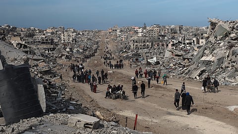 Palestinians walk through the destruction caused by the Israeli air and ground offensive in Jabaliya, as a ceasefire deal between Israel and Hamas went into effect, Sunday, Jan. 19, 2025.