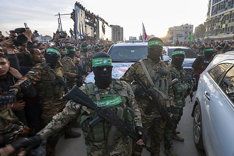 Hamas fighters escort a Red Cross vehicle to collect Israeli hostages released after a ceasefire agreement between Israel and Hamas took effect, in Gaza City Sunday, Jan. 19, 2025.