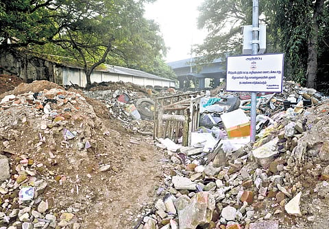 Heaps of construction waste found around a board that warns of legal action against people dumping debris, on Swami Sivananda Salai