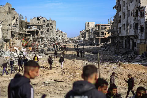 Palestinians walk amongst the destruction caused by the Israeli air and ground offensive, Sunday, Jan. 19, 2025, in Rafah, as a ceasefire deal between Israel and Hamas went into effect.