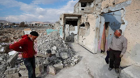 Samir al-Baghdadi, 46, left, stands on his brother Fayez outside his family's home that was destroyed during the civil war in the Qaboun neighbourhood of Damascus, Syria, Saturday, Jan. 11, 2025.