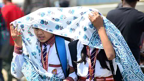In this image from March 28, 2024, school students cover themselves with a scarf during a hot summer day in Prayagraj, Uttar Pradesh.