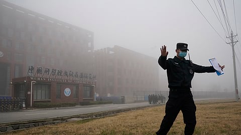 In this photo from Feb. 3, 2021, a security person moves journalists away from the Wuhan Institute of Virology after a World Health Organization team arrived for a field visit in Wuhan in China's Hubei province.