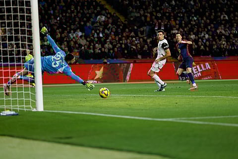 Barcelona's Robert Lewandowski, right, scores his side's sixth goal past Valencia's goalkeeper Giorgi Mamardashvili during the Spanish La Liga soccer match between Barcelona and Valencia on Sunday, Jan. 26, 2025.