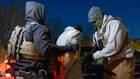 US Immigration and Customs Enforcement officers use a chain to more comfortably restrain a detained person using handcuffs positioned in front, Monday, Jan. 27, 2025, in Silver Spring, Md.