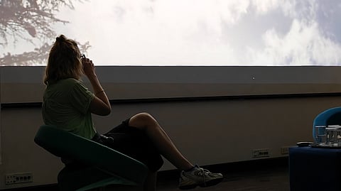 Sina sits to the left of the stage, sipping tea. She watches the video, unfazed.