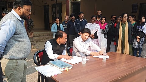 Collector Gaurav Singh (L) examining staff attendance