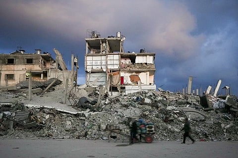 A man pushes a cart past a house that remains partly standing, but with sheets serving as makeshift walls, in an area largely destroyed by the Israeli army's air and ground offensive in Gaza City, Gaza Strip, Wednesday, Feb. 5, 2025.