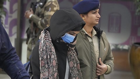 An Indian police official escorts an immigrant woman, wearing mask, deported from the United States, who was among those who arrived in a U.S. military plane Wednesday in Amritsar, upon her arrival at the Ahmedabad airport in India, Thursday, Feb. 6, 2025.
