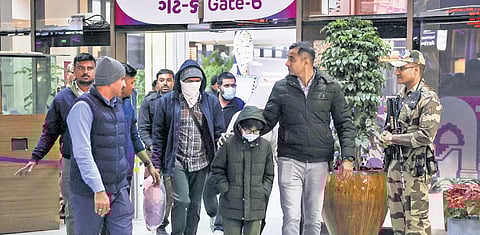 Security personnel escort Gujarat immigrants deported from the US after they were brought to the Ahmedabad airport on Thursday.