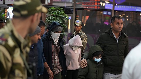 Indian police officials escort immigrants, wearing mask, deported from the United States, who were among those who arrived in a U.S. military plane Wednesday in Amritsar, upon their arrival at the Ahmedabad airport in India, Thursday, Feb. 6, 2025.