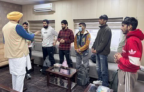 Punjab NRI Affairs Minister Kuldeep Singh Dhaliwal, front left, interacts with illegal Indian immigrants, who were deported from the US, upon their arrival, in Amritsar,