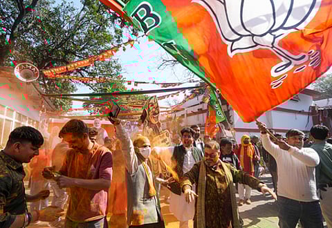 BJP supporters celebrate the party's decisive lead in the Delhi Assembly polls as counting of votes is underway, outside the Delhi BJP office.