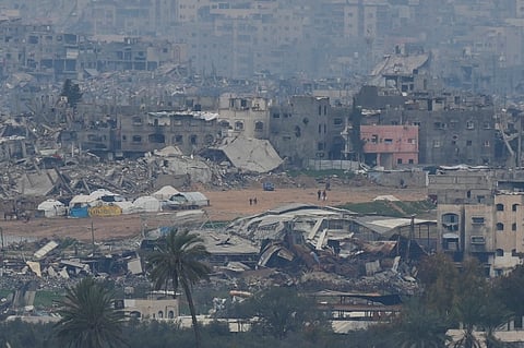 Palestinians are seen near destroyed buildings by Israeli bombardments inside the northern Gaza Strip as seen from southern Israel, Sunday, Feb. 9, 2025.
