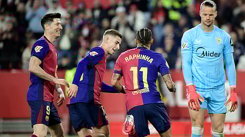 Barcelona's Brazilian forward Raphinha celebrates with Robert Lewandowski and Fermin Lopez after scoring his team's third goal during the Spanish league football match between Sevilla FC and FC Barcelona on February 9, 2025.