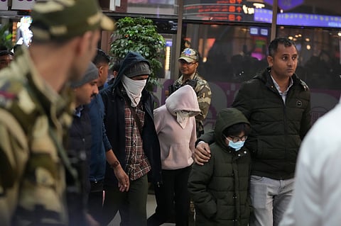 Indian police officials escort immigrants, wearing mask, deported from the United States, who were among those who arrived in a U.S. military plane Wednesday in Amritsar, upon their arrival at the Ahmedabad airport in India, Thursday, Feb. 6, 2025.